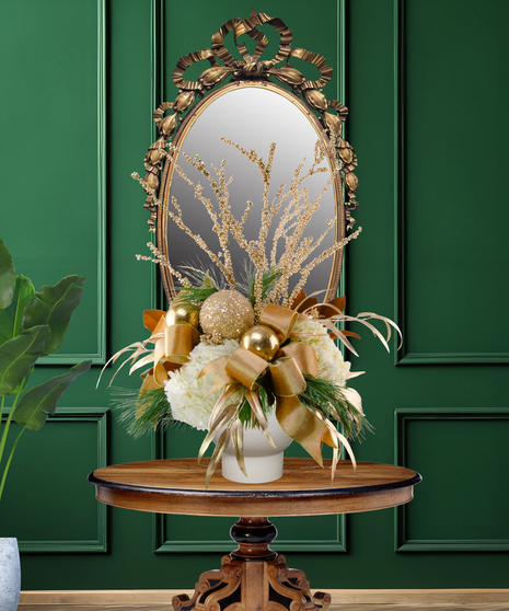 24 Karat Christmas luxury flower arrangement with white lilies, white hydrangeas, gold ornaments, gilded branches, and gold ribbon in a gold vase