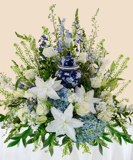 A Touch of Color Cremation Arrangement with white lilies, roses, blue hydrangeas, and greenery surrounding an urn of your choice.