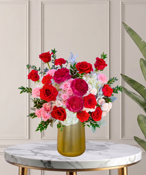 Another Year Loving You flower arrangement with red roses, pink garden roses, blush spray roses, and hydrangeas in a tall white vase