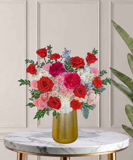 Another Year Loving You flower arrangement with red roses, pink garden roses, blush spray roses, and hydrangeas in a tall white vase