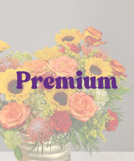Autumn floral arrangement with sunflowers, orange roses, red carnations, and greenery in a gold vase