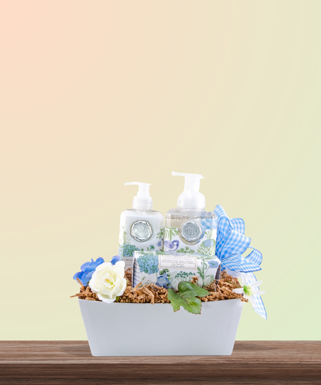 Serenity for Mom gift basket with cotton & linen-scented spa products, floral accents, and ivory ribbon in a woven basket – Mother’s Day gift idea.