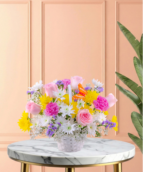 Basket of Blooms Easter flower arrangement featuring roses, mums, carnations, baby's breath, and an orange butterfly decoration in a classic white woven basket
