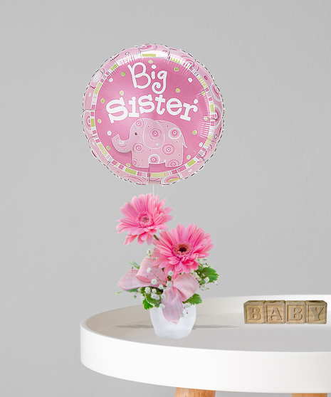 Pink Gerbera daisy arrangement in a white vase with a pink bow and a 