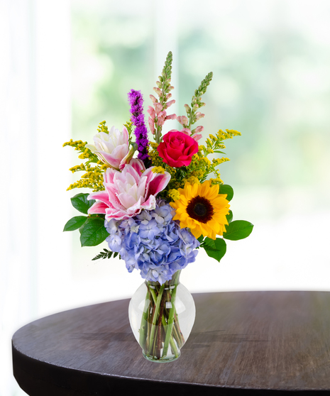 Brighten Her Day flower arrangement with sunflowers, hydrangeas, roses, lilies, and liatris in a glass vase – Admin Week appreciation bouquet.