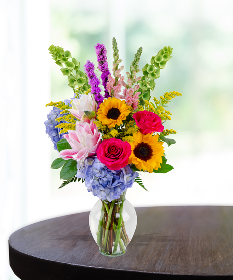 Brighten Her Day flower arrangement with sunflowers, hydrangeas, roses, lilies, and liatris in a glass vase – Admin Week appreciation bouquet.