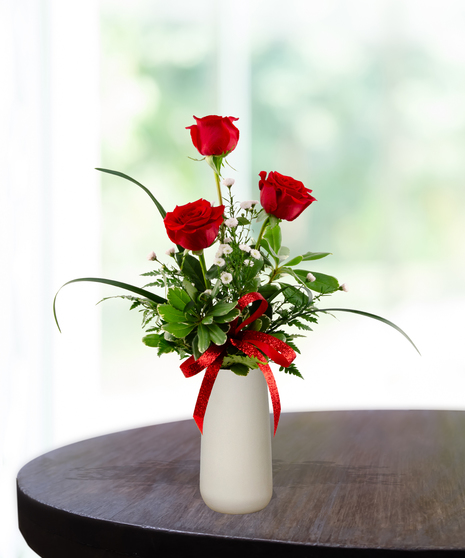 Valentine Bud Vase with six red roses, white baby's breath, and a red glitter ribbon in a tall white ceramic vase.