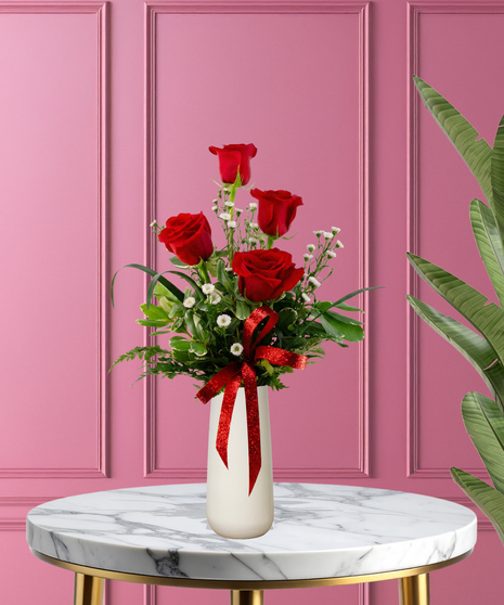 Valentine Bud Vase with six red roses, white baby's breath, and a red glitter ribbon in a tall white ceramic vase.