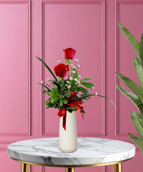 Valentine Bud Vase with six red roses, white baby's breath, and a red glitter ribbon in a tall white ceramic vase.