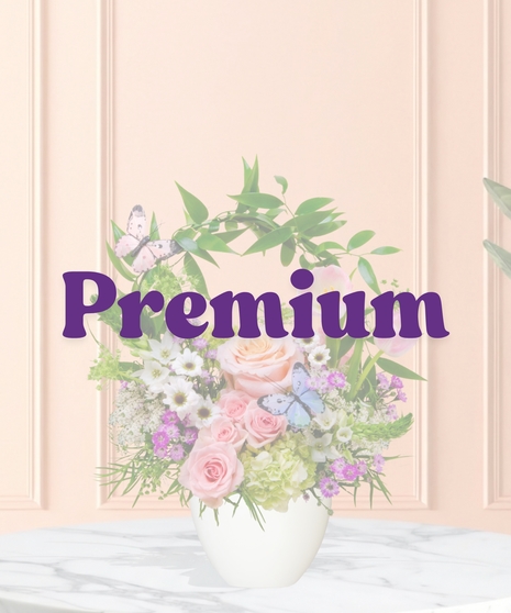 Butterfly Brunch flower arrangement with peach roses, tulips, hydrangeas, daisies, and butterfly accents in a pedestal vase with arched greenery.