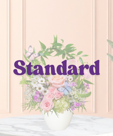 Butterfly Brunch flower arrangement with peach roses, tulips, hydrangeas, daisies, and butterfly accents in a pedestal vase with arched greenery.