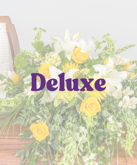 Golden and white casket spray with yellow roses, white lilies, bells of Ireland, and cascading greenery from Billy Heroman’s in Baton Rouge