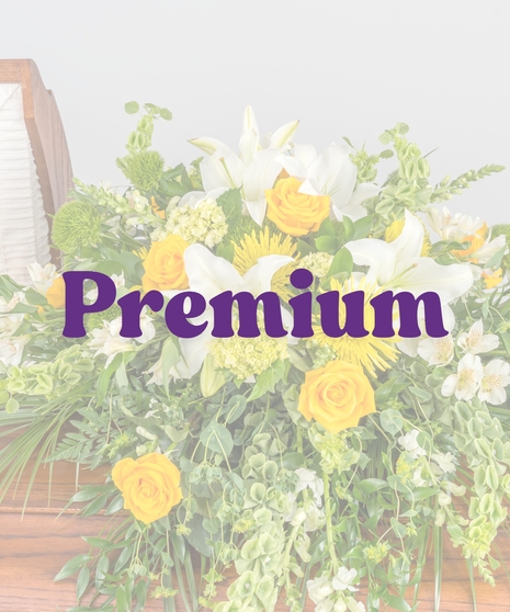 Golden and white casket spray with yellow roses, white lilies, bells of Ireland, and cascading greenery from Billy Heroman’s in Baton Rouge