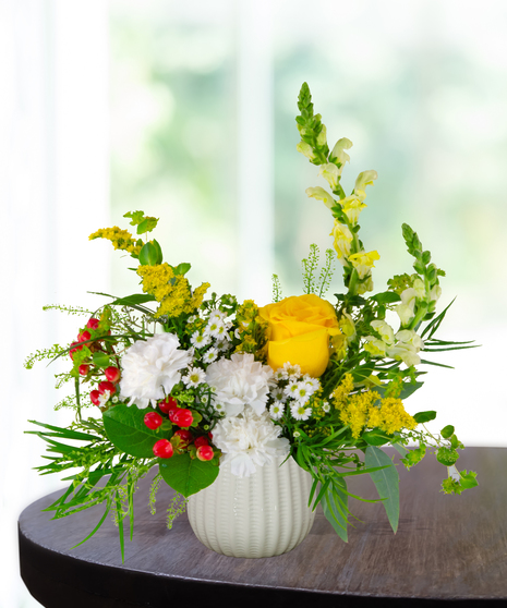 Banana Split flower arrangement with yellow roses, white carnations, red berries, and assorted greenery in a white vase