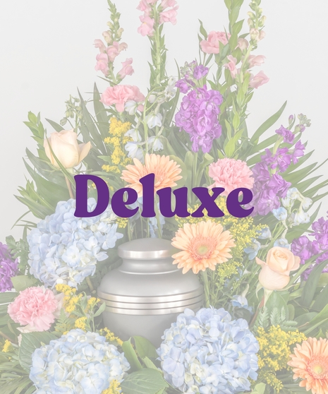 Colorful cremation urn flower arrangement with blue hydrangea, gerbera daisies, and spring blooms from Billy Heroman’s Florist in Baton Rouge