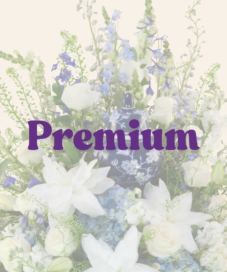 A Touch of Color Cremation Arrangement with white lilies, roses, blue hydrangeas, and greenery surrounding an urn of your choice.