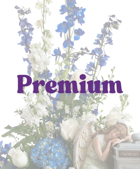 Cremation arrangement featuring white roses, blue hydrangea, and a sleeping angel figurine next to a stone urn with engraved message