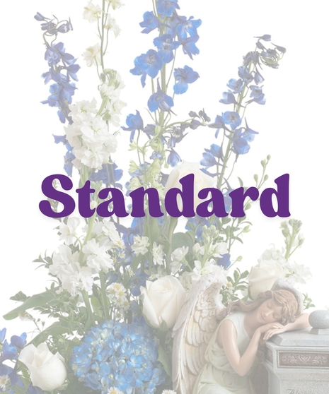 Cremation arrangement featuring white roses, blue hydrangea, and a sleeping angel figurine next to a stone urn with engraved message