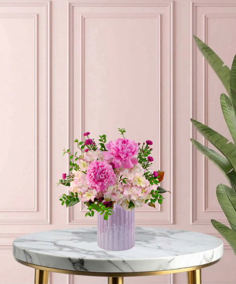 Crown Jewel Signature flower arrangement featuring large pink peonies, magenta garden roses, and lush pink hydrangeas in a ridged lavender glass vase.