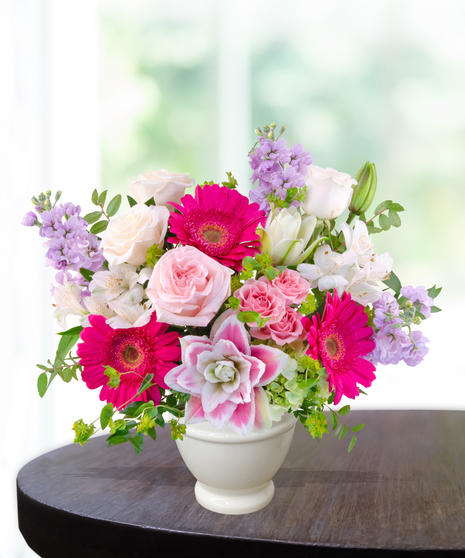 Pink Carats floral arrangement featuring pink roses, gerbera daisies, lilies, hydrangeas, and spring blooms in an ivory vase – an April birthday exclusive.