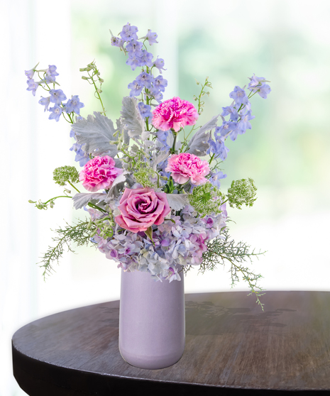 Lavender Haze flower arrangement with lilies, pink roses, blue hydrangeas, and delphinium in a lavender vase