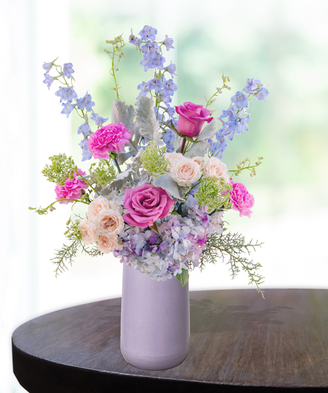Lavender Haze flower arrangement with lilies, pink roses, blue hydrangeas, and delphinium in a lavender vase