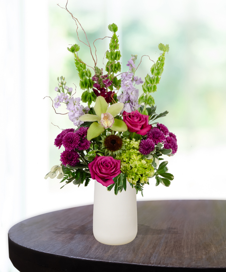 Green and purple birthday flower arrangement with orchids, roses, and hydrangeas