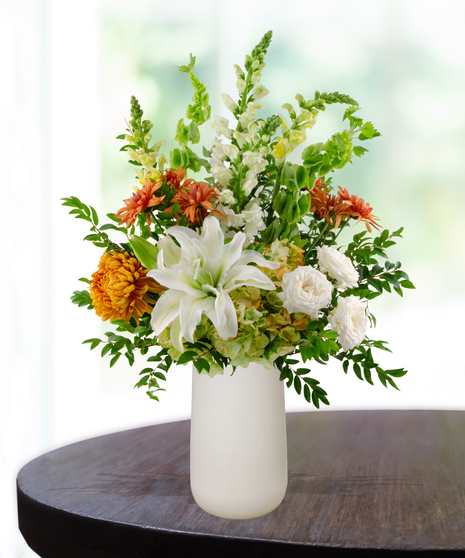 Topaz to Remember November birthday flower arrangement with white lilies, white roses, orange mums, and green Bells of Ireland in a white vase