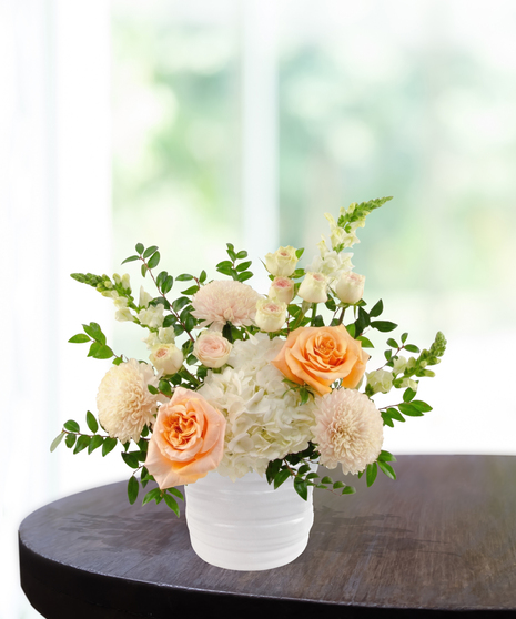 Just Peachy exclusive April birthday flower arrangement with peach garden roses, cream spray roses, white hydrangeas, and snapdragons in a ridged white vase.