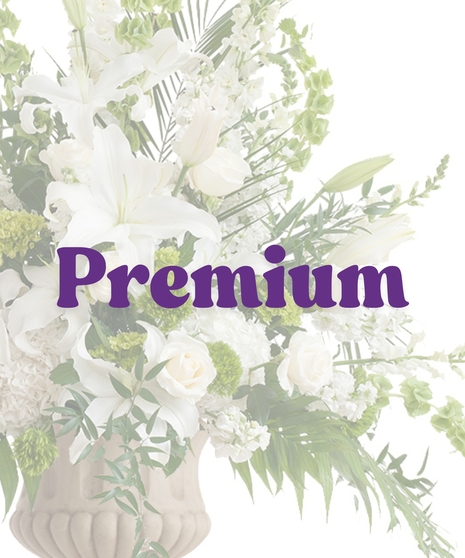 Elegant White Urn Arrangement with white lilies, roses, hydrangeas, and bells of Ireland in a tall stone urn
