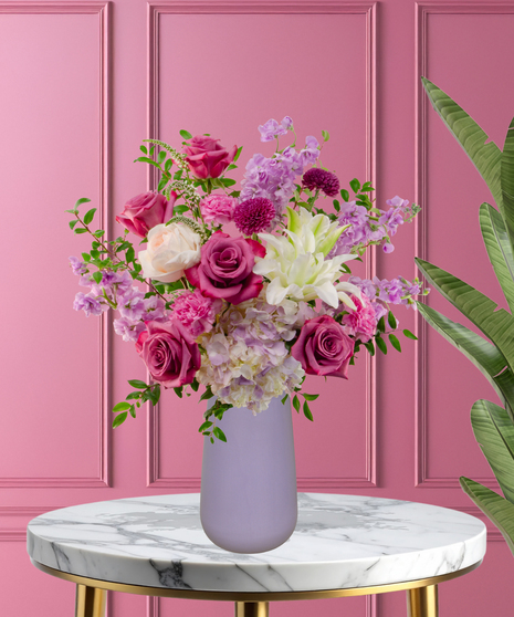 Pretty in Purple exclusive Valentine's and February birthday flower arrangement with lavender roses, white lilies, purple stock, and magenta mums in a frosted lavender vase.
