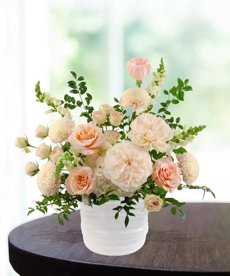 She's A Peach exclusive April birthday flower arrangement with peach garden roses, cream spray roses, white hydrangeas, and snapdragons in a ridged white vase.