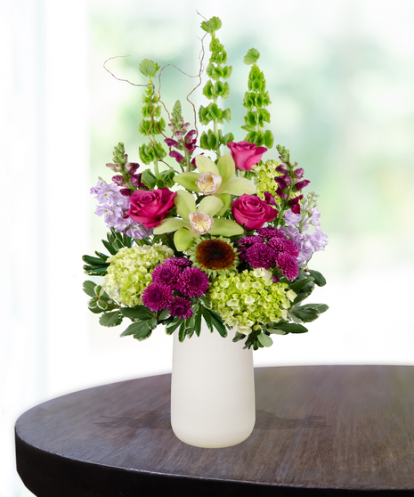Green and purple birthday flower arrangement with orchids, roses, and hydrangeas