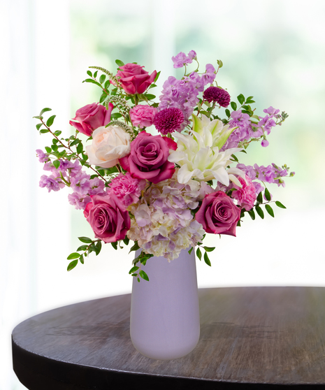 Pretty in Purple exclusive Valentine's and February birthday flower arrangement with lavender roses, white lilies, purple stock, and magenta mums in a frosted lavender vase.
