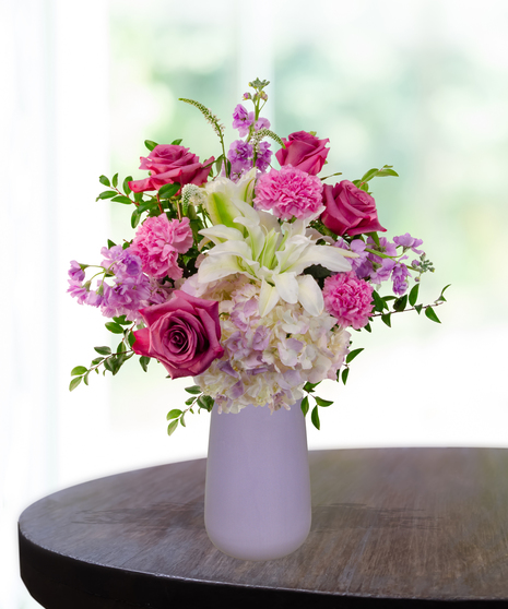 Pretty in Purple exclusive Valentine's and February birthday flower arrangement with lavender roses, white lilies, purple stock, and magenta mums in a frosted lavender vase.