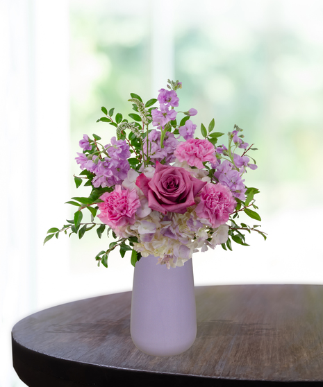 Pretty in Purple exclusive Valentine's and February birthday flower arrangement with lavender roses, white lilies, purple stock, and magenta mums in a frosted lavender vase.