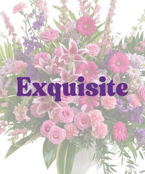 Feminine urn floral arrangement with pink rose lilies, roses, carnations, gerbera daisies, purple stock, and greenery in a white pedestal vase
