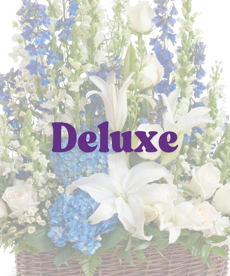 Sympathy floor arrangement in blue and white with lilies, hydrangea, roses, and snapdragons in a brown basket