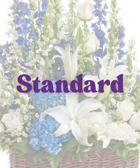Sympathy floor arrangement in blue and white with lilies, hydrangea, roses, and snapdragons in a brown basket
