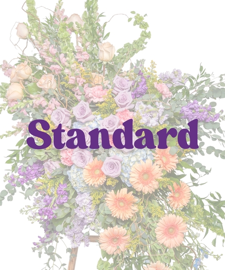 Pastel standing spray with lavender roses, peach gerberas, hydrangea, and garden blooms on a wooden easel from Billy Heroman’s in Baton Rouge