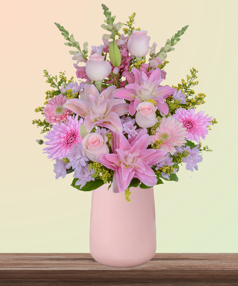 Mother’s Glow flower arrangement with pink lilies, blush roses, gerbera daisies, snapdragons, and hydrangeas in a matte pink vase – a Mother’s Day bouquet.