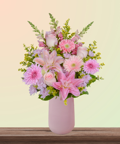 Mother’s Glow flower arrangement with pink lilies, blush roses, gerbera daisies, snapdragons, and hydrangeas in a matte pink vase – a Mother’s Day bouquet.