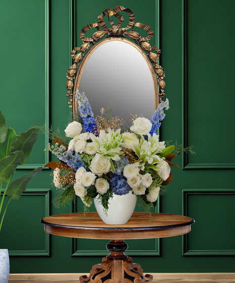 Miracle of Lights Hanukkah flower arrangement with white roses, white lilies, blue delphinium, blue thistle, green spider mums, and magnolia leaves in a white vase