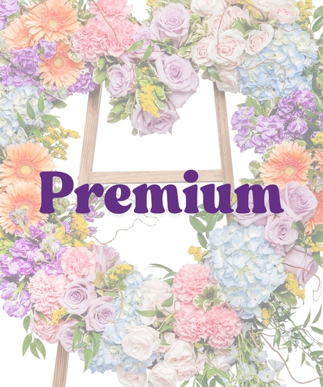 Pastel heart-shaped floral tribute with gerbera daisies, roses, hydrangea, and greenery on a wooden easel from Billy Heroman’s Florist in Baton Rouge