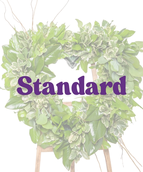 Green heart-shaped funeral wreath of magnolia and foliage on an easel from Billy Heroman’s Florist in Baton Rouge