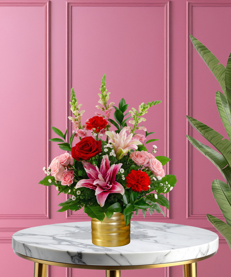 Heart Throb luxury Valentine's arrangement with red roses, pink-tipped lilies, red and pink carnations, and white baby's breath in a ribbed gold metallic vase.