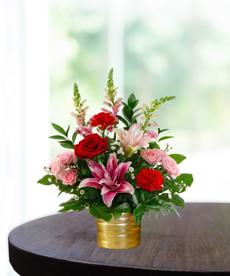 Sugar & Spice flower arrangement featuring red roses, pink lilies, red carnations, and pink snapdragons in a luxury gold ribbed vase