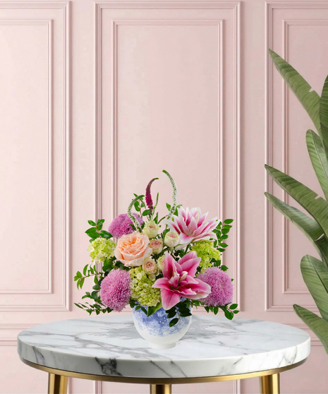 Heart of the Home Mother's Day flower arrangement featuring peach garden roses, pink and white rose lilies, lavender mums, and veronica in a marbled blue and white bowl.