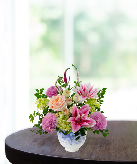 Heart of the Home Mother's Day flower arrangement featuring peach garden roses, pink and white rose lilies, lavender mums, and veronica in a marbled blue and white bowl.