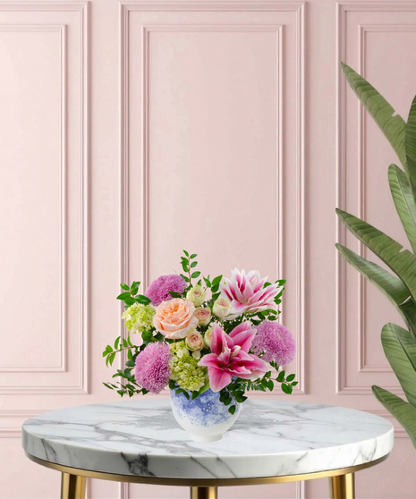 Heart of the Home Mother's Day flower arrangement featuring peach garden roses, pink and white rose lilies, lavender mums, and veronica in a marbled blue and white bowl.
